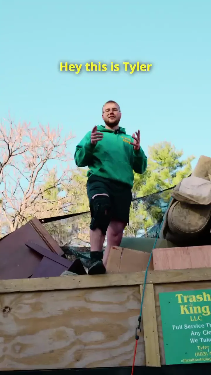 Trash King owner Tyler Farmer standing on top of a full truck load of removed junk