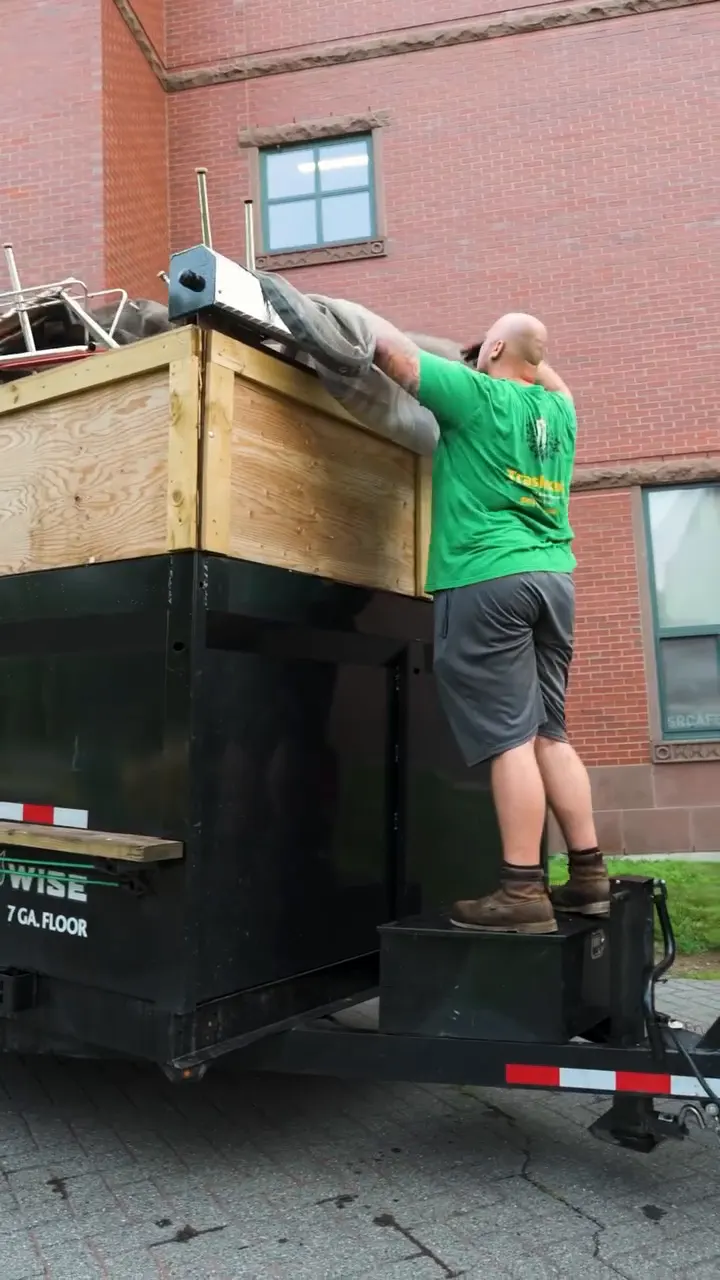 Trash King crew clearing old desks and chairs from a school classroom and loading them into the dump trailer